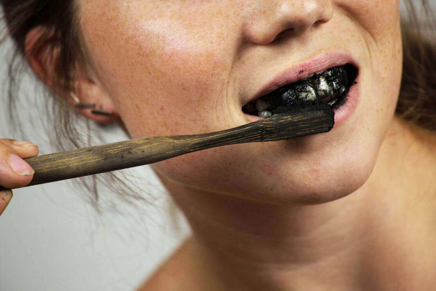 persona cepillándose los dientes con carbón activo en polvo